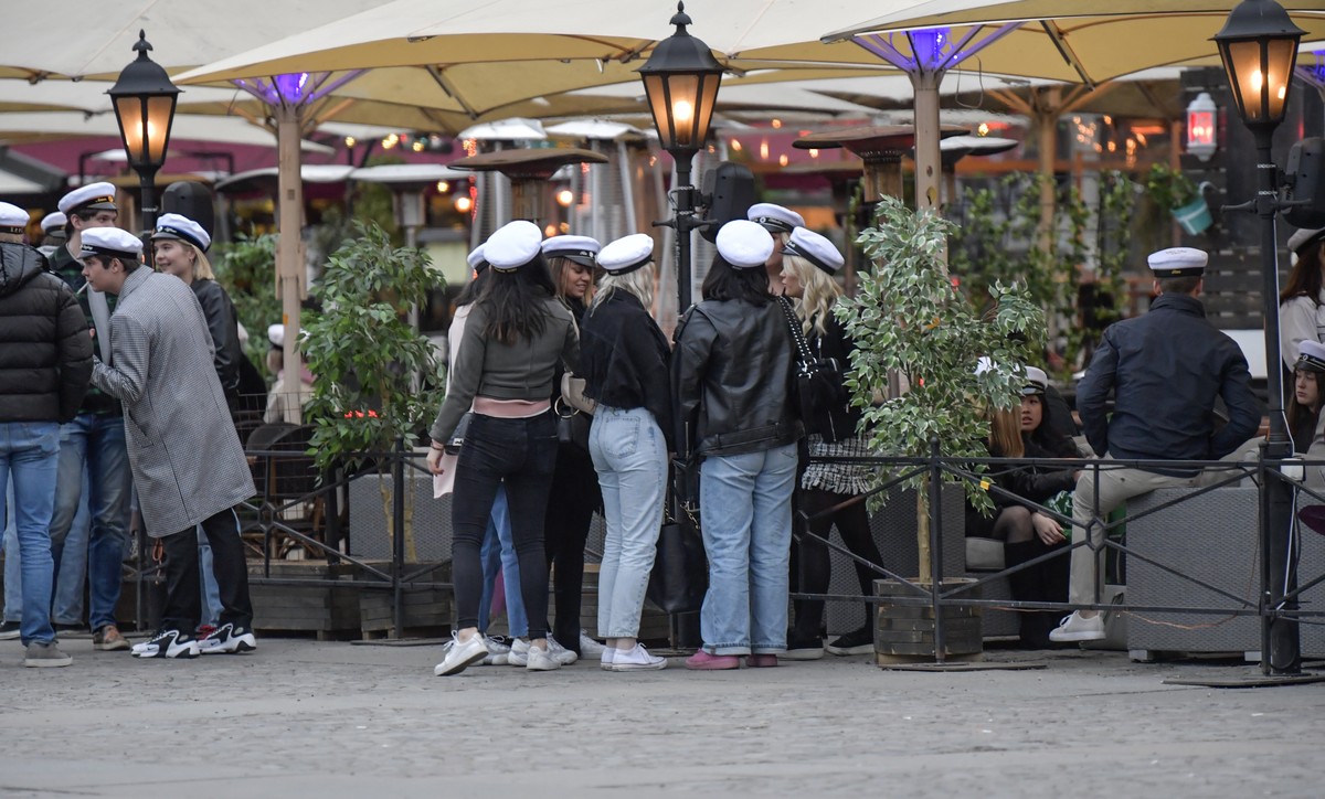 epa08383798 Senior high school students celebrate their graduation wearing the traditional white caps while drinking on the terrace of a restaurant in downtown Stockholm, Sweden, 24 April 2020 (issued ...