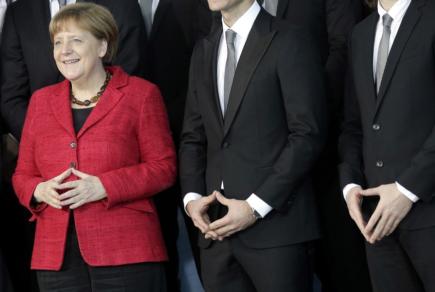 FILE - In this March 9, 2016 file photo Chancellor Angela Merkel, left, and team members make Merkel&#039;s trademark gesture as they pose for the media during a reception for the German National Hand ...