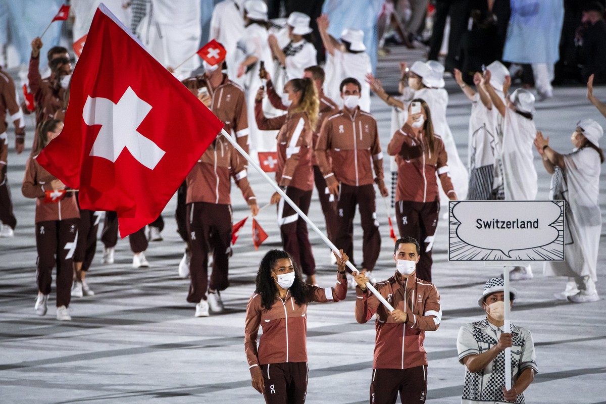 epa09359857 Switzerland's flag-bearers sprinter Mujinga Kambundji and epee fencer Max Heinzer during the opening ceremony of the 2020 Tokyo Summer Olympics at the National Stadium in Tokyo, Japan ...