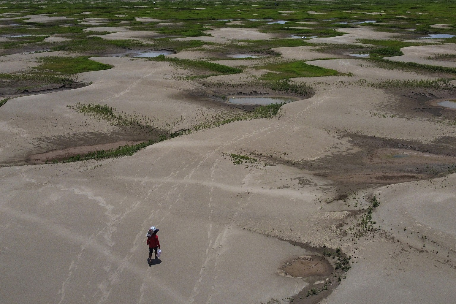 FILE - A resident of a riverside community carries food and containers of drinking water after being distributed due to the ongoing drought in Careiro da Varzea, Amazonas state, Brazil, Oct. 24, 2023. ...