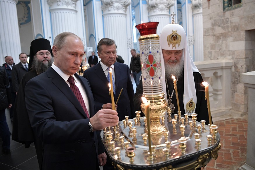 epa06331416 Russian President Vladimir Putin (L) lights a candle as Russian Orthodox Patriarch Kirill of Moscow and All Russia (R) and Gazprom Board of Directors Chairman Viktor Zubkov (C) attend as t ...