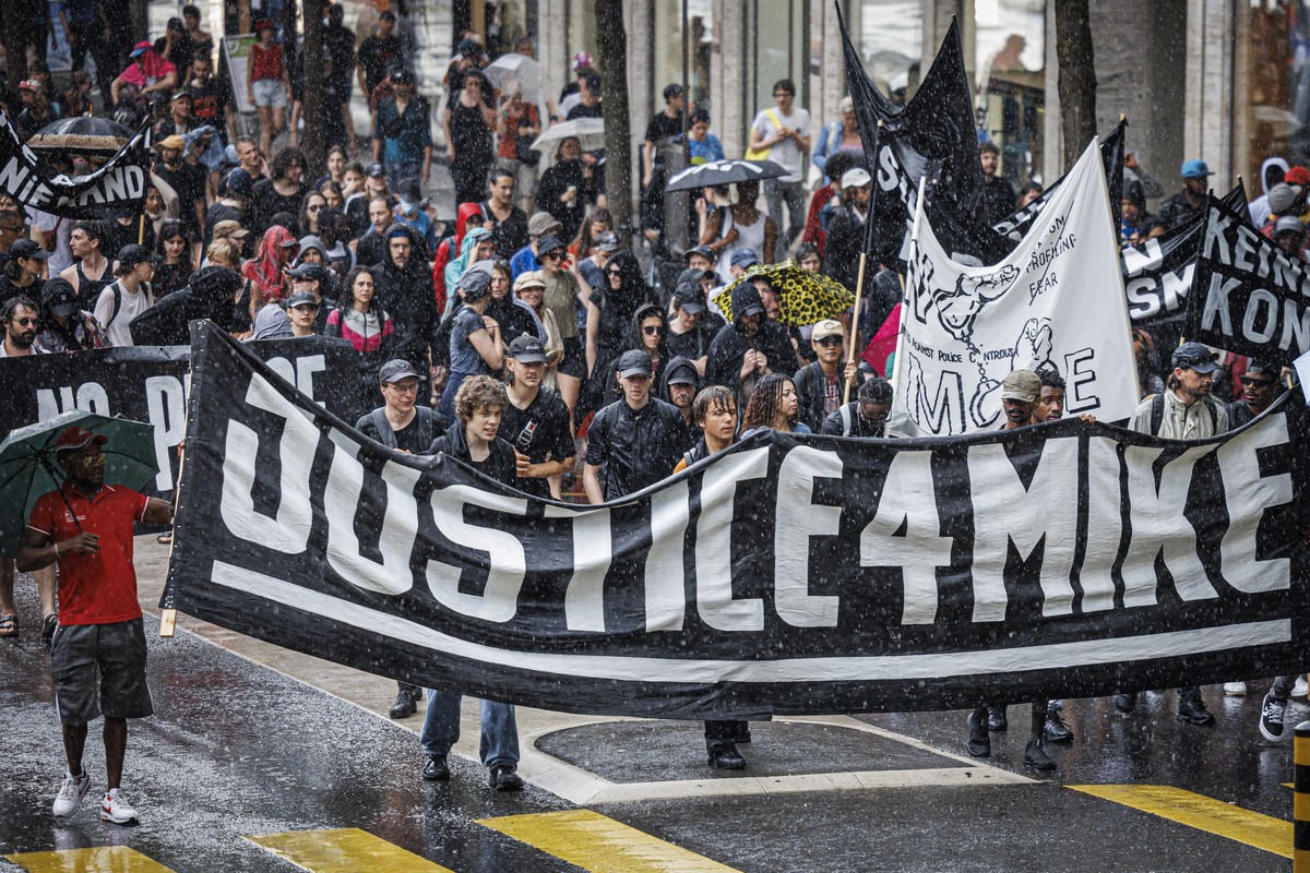 Des personnes marchent en cortege sous la pluie lors d'une manifestation en hommage a Mike Ben Peter et contre le racisme, ce samedi 3 juin 2023 a Lausanne. Des le 12 juin s'ouvrira le proce ...