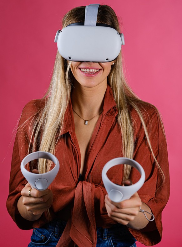 ANTWERP, BELGIUM - Jan 30, 2021: A portrait of young woman holding VR controllers with Meta Quest headset, trying for first time