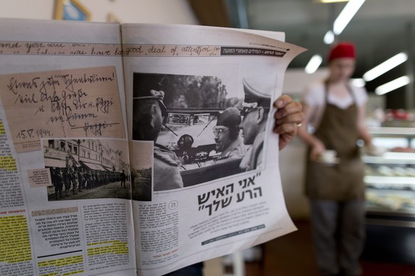 epa04042634 An Israeli in a cafe in Mevaseret Zion, Israel, 26 January 2014, shows the leading Israeli newspaper Yedioth Ahronoth where a large section is devoted to the diaries of Heinrich Himmler, t ...