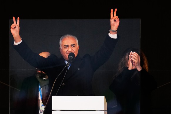 Iran's exiled Crown Prince Reza Pahlavi, left, and his wife Yasmine Pahlavi wave to supporters at a demonstration during the Munich Security Conference in Munich, Germany, Saturday, Feb. 14, 2026 ...