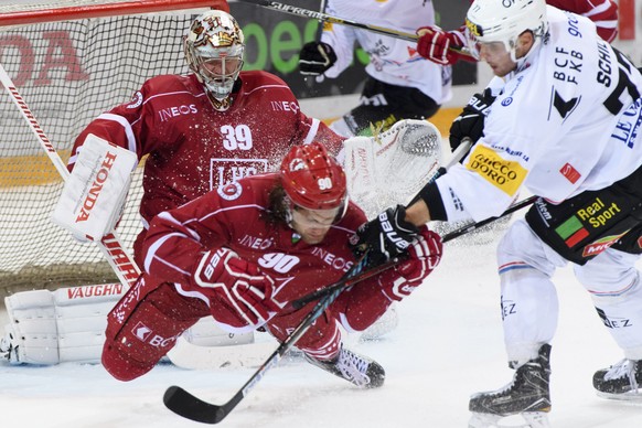 Le defenseur lausannois Jannik Fischer, centre, et le gardien lausannois Cristobal Huet, gauche derriere, luttent pour le puck avec le defenseur fribourgeois Sebastian Schilt, droite, lors du match du ...