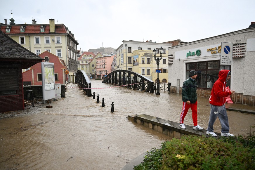 epa11605256 People pass by next to a flooded street after the heavy rainfalls caused the flooding in Klodzko, southwestern Poland, 15 September 2024. The next 24-36 hours will be crucial for the south ...