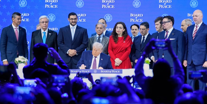 US President Donald Trump signs the charter of his Board of Peace initiative at the Annual Meeting of the World Economic Forum in Davos, Switzerland, Thursday, Jan. 22, 2026. (AP Photo/Markus Schreibe ...