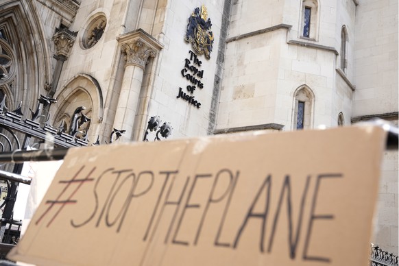 FILE - A placard left outside the High Court where the ruling on Rwanda deportation flights is taking place, in London Monday, June 13, 2022. British Foreign Secretary Liz Truss says the first deporta ...