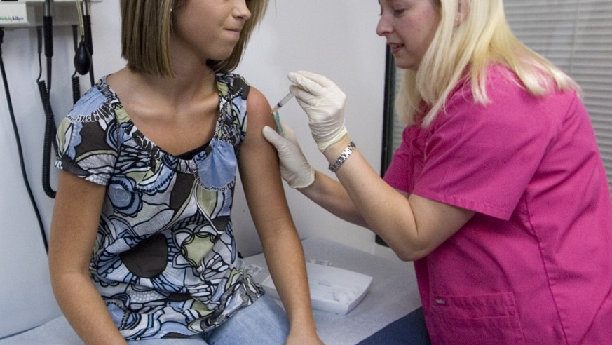 FILE - In this Dec. 18, 2007 file photo, Lauren Fant, left, winces as she has her third and final application of the Human Papillomavirus (HPV) vaccine administered by nurse Stephanie Pearson at a doc ...