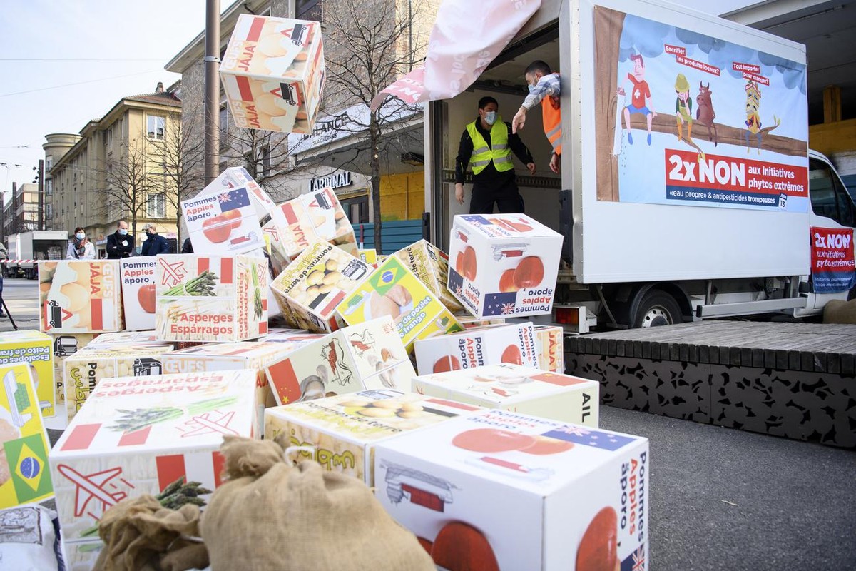 Des personnes lancent des cartons representant de la nourriture importee lors du lancement de la campagne romande du non aux initiatives "Pour une Suisse libre de pesticides de synthese" et  ...