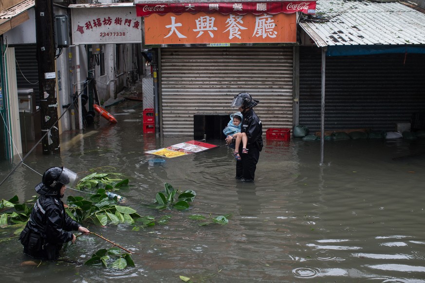 epa07024364 Police officers rescue a child from a flooded street during Typhoon Mangkhut in Lei Yu Mun, Hong Kong, China, 16 September 2018. The No 10 typhoon warning was raised in the early hours as  ...