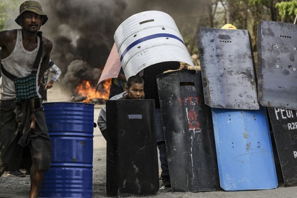 epa09073612 Demonstrators takes cover behind metal shields during a protest against the military coup in Hlaingthaya (Hlaing Tharyar) Township, outskirts of Yangon, Myanmar, 14 March 2021. Anti-coup p ...