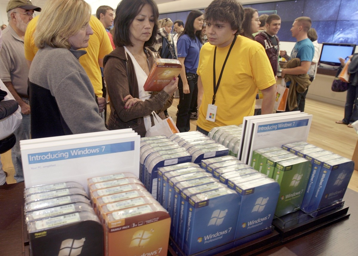 Customers Donna Witulski, left, and Vickie Youseff, center, ask questions of Microsoft&amp;#039;s newly-released operating system, Windows 7, to store employee James Vallejo, right, during the grand o ...