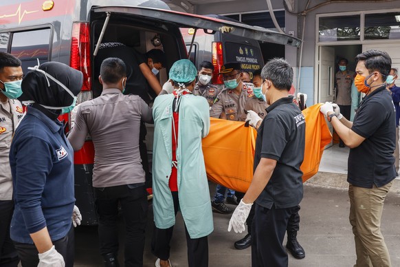 epa09454477 Disaster Victims Identification (DVI) police officers load a body bag onto a van in the aftermath of a prison fire, at a hospital in Tangerang, Banten, Indonesia, 08 September 2021. A fire ...