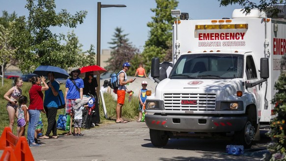 A Salvation Army EMS vehicle is setup as a cooling station as people lineup to get into a splash park while trying to beat the heat in Calgary, Alberta., Wednesday, June 30, 2021. Environment Canada w ...