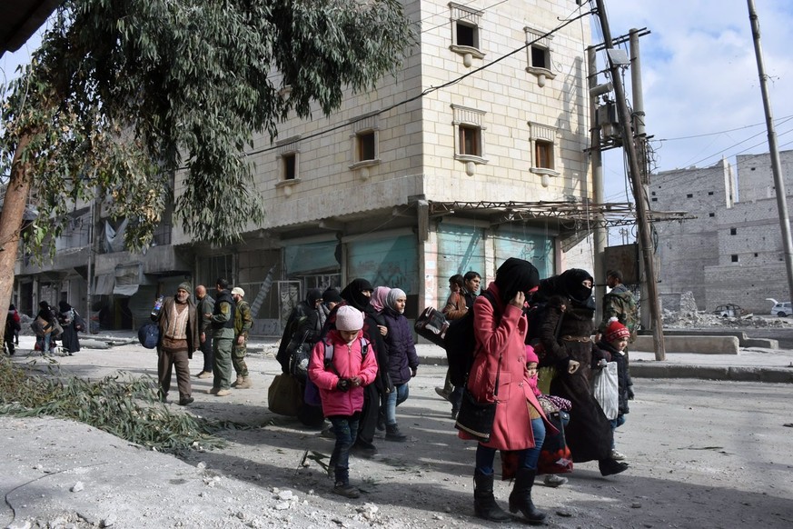 epa05673957 A handout photograph released by the official Syrian Arab News Agency (SANA) on 13 December 2016 showing people evacuating a neighborhood in Aleppo after government forces recaptured it fr ...