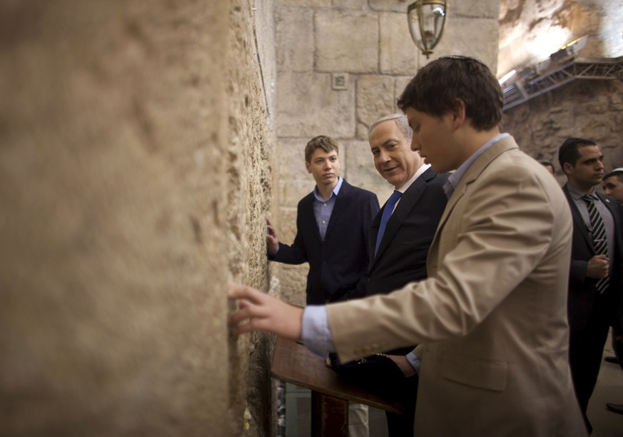 FILE - In this Jan. 22, 2013 file photo, Israeli Prime Minister Benjamin Netanyahu, center, prays with his sons Yair left, and Avner at the Western Wall, the holiest site where Jews can pray in Jerusa ...