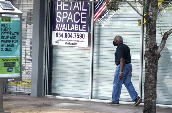 epa08716065 A man walks next to a closed store, in Downtown Miami, Florida, USA, 02 October 2020. Fewer Floridians filed for unemployment last week than in any week since the COVID-19 pandemic began.  ...