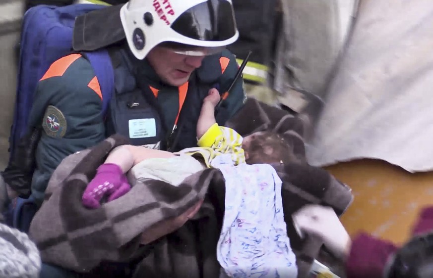 This photo provided by the Russian Emergency Situations Ministry taken from tv footage shows a Emergency Situations employee carries a saved 10 month old baby at the scene of a collapsed section of an ...