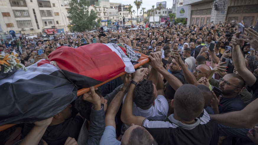 Palestinian mourners carry the body of Shireen Abu Akleh out of the office of Al Jazeera after friends and colleagues paid their respects, in the West Bank city of Ramallah, Wednesday, May 11, 2022. V ...