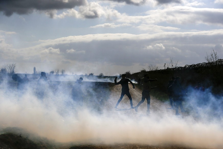 Migrants gather at a border fence on the Turkish side during clashes with the Greek riot police and army at the Turkish-Greek border in Pazarkule, Edirne region, on Saturday, March 7, 2020. Thousands  ...