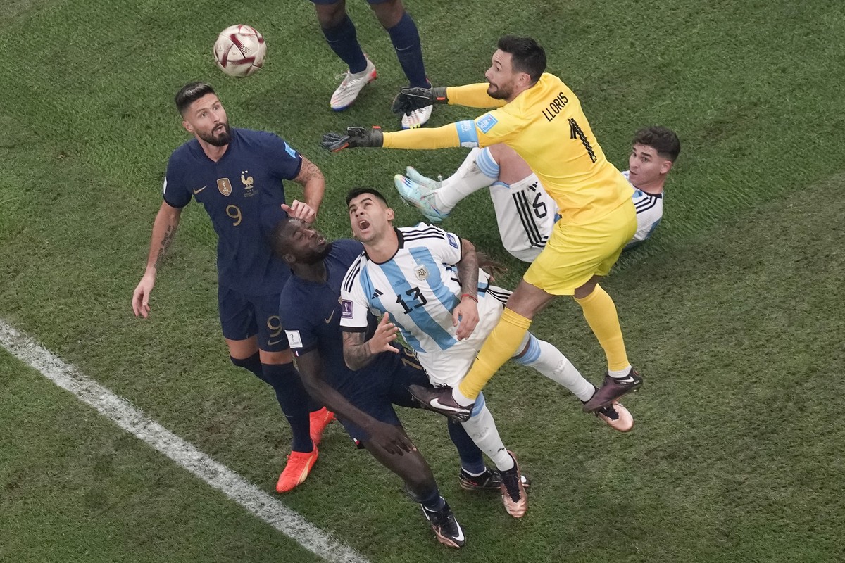 France's goalkeeper Hugo Lloris saves as Argentina's Cristian Romero, with number 13, tries to head the ball during the World Cup final soccer match between Argentina and France at the Lusai ...