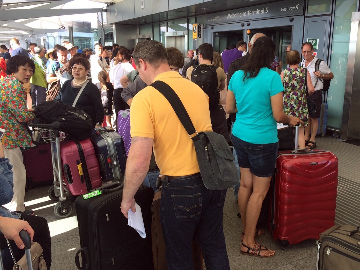 Passengers stand with their luggage outside Terminal 5 at London's Heathrow airport after flights were canceled due to the airport suffering an IT systems failure, Saturday, May 27, 2017. British ...