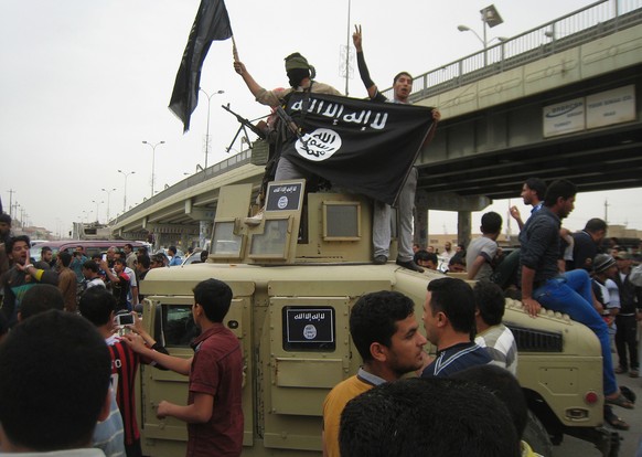 FILE - in this Sunday, March 30, 2014, file photo, Islamic State group militants hold up their flag as they patrol in a commandeered Iraqi military vehicle in Fallujah, 40 miles (65 kilometers) west o ...