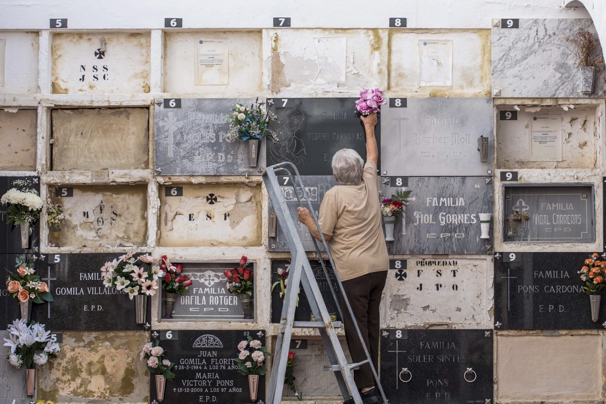 epa10950870 A person decorates the graves of a departed relative at the cementery of Sant Lluis in Menorca, Balearic Islands, Spain, 31 October 2023, on the eve of the All Saints' Day. Millions o ...