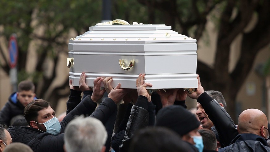 Pallbearers holds aloft a white casket during the funeral ceremony for a 10-year-old girl who died while participating in a so-called