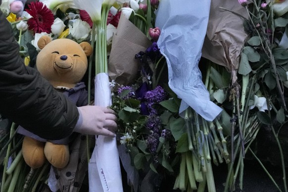 People lay flowers for the victims near the Vladislav Ribnikar school in Belgrade, Serbia, Wednesday, May 3, 2023. Police say a 13-year-old who opened fire at his school drew sketches of classrooms an ...