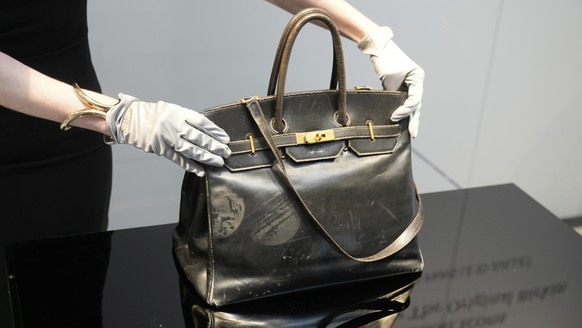 An auction officer displays the original Birkin bag created by Herm