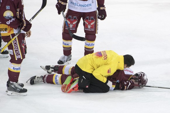 Noah Rod, Mitte, von Servette, liegt nach einem zusammenstoss benommen auf dem Eis beim Eishockey Meisterschaftsspiel zwischen dem EV Zug und Geneve Servette HC vom Montag, 2. Januar 2017, in Zug. (KE ...