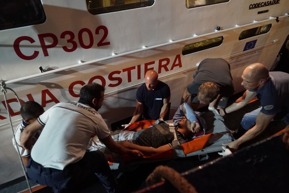 epa07676749 A handout photo made available by Sea-Watch on 27 June 2019 shows members of the Italian Coast Guard (Guardia Costiera) evacuating a young man as a medical emergency from the Sea-Watch 3 v ...