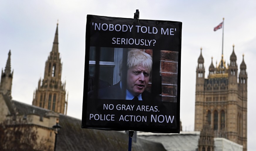 epa09695189 A protester holds a placard showing British Prime Minister Boris Johnson, outside parliament in London, Britain, 19 January 2022. Pressure is building on British Prime Minister Boris Johns ...