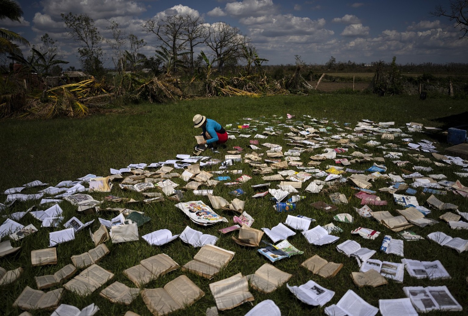 A teacher puts dries out books at a school that was heavily damaged by Hurricane Ian in La Coloma, in the province of Pinar del Rio, Cuba, Wednesday, Oct. 5, 2022. (AP Photo/Ramon Espinosa)