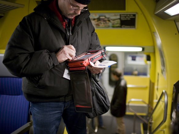 A civilian inspector checks the validity of a season ticket with his specialized portable computer in the S3 train on the way between Zurich and Lenzburg, Switzerland, during a top priority check of t ...