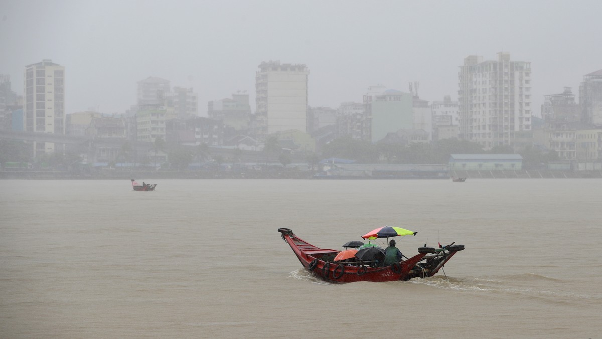 epa13104491 People travel by boat under the rain on the Yangon river in Dala Township across downtown Yangon, Myanmar, 11 July 2026. The Myanmar Port Authority issued a warning to residents living alo ...