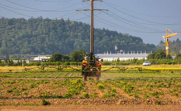 Ein Bauer besprüht sein Feld mit einer unbekannten Substanz. Möglicherweise Düngemittel, oder Pflanzenschutzmittel. (Rafz, Schweiz, 03.06.2023) *** A farmer sprays his field with an unknown substance  ...