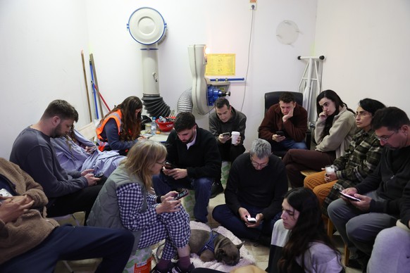 epa12786359 People sit in a shelter in Tel Aviv, Israel, 01 March 2026. The Israeli military reported on 28 February it detected missiles launched from Iran following earlier Israeli and US strikes on ...