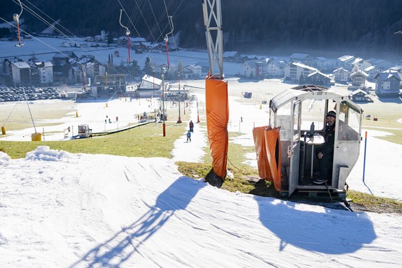 Skifahrer vergnuegen sich auf der Kunstschneepiste der Klostermatte in gruener Landschaft, aufgenommen am Samstag, 7. Januar 2023, in Engelberg im Kanton Obwalden. (KEYSTONE/Urs Flueeler). People enjo ...
