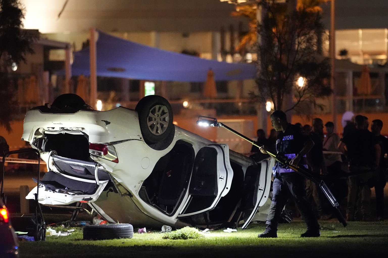 Israeli police and emergency services work around a car involved in an attack in Tel Aviv, Israel, Friday, April 7, 2023. Israeli police said a car rammed into a group of people near a popular seaside ...