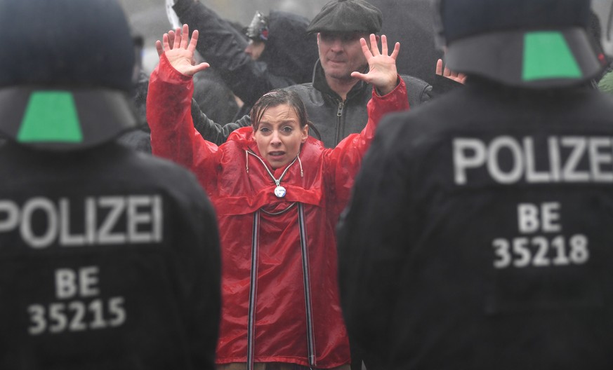 epa08827259 A protester raises her arms while the police attempts to break up a demonstration against German coronavirus restrictions in front of the Brandenburg Gate in Berlin, Germany, 18 November 2 ...