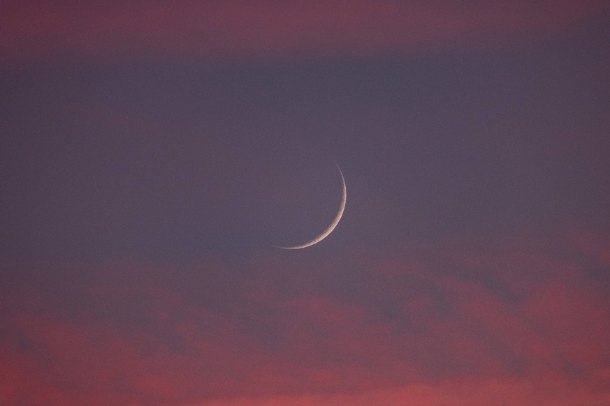 Two days old new moon in the sky over Aachen against a background of pink clouds that owe their color to the sunset. In Aachen on June 12, 2021 GERMANY - AACHEN - WEATHER