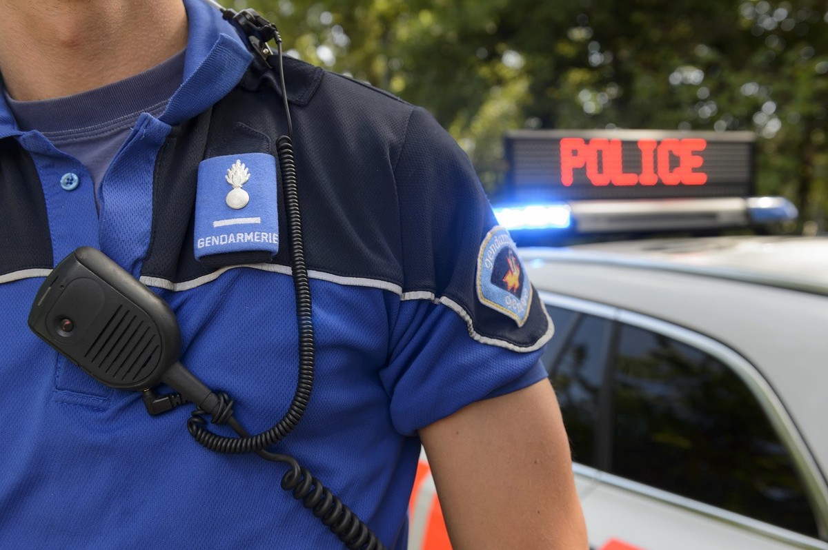 Un policier de la Police cantonale genevoise pose a cote d'un panneau indiquant police sur une voiture, pour des photos d'illustration, ce vendredi 31 juillet 2015 a Geneve. (KEYSTONE/Martia ...