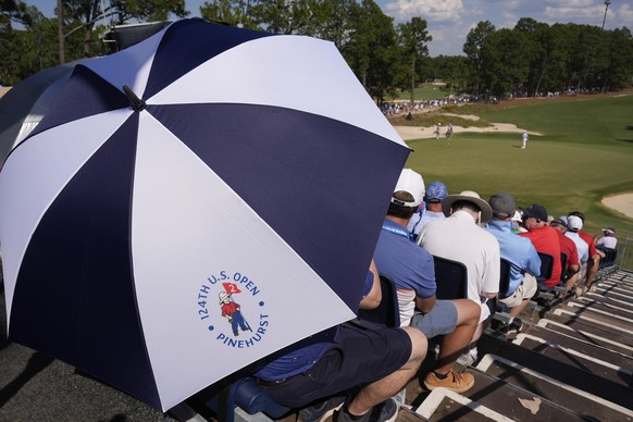 A fan hides from heat on the 16th hole during the third round of the U.S. Open golf tournament Saturday, June 15, 2024, in Pinehurst, N.C. (AP Photo/George Walker IV)