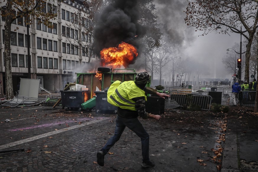 epa07201218 Protesters wearing yellow vests (gilets jaunes) clash with riot police near a burning barricade during a demonstration over high fuel prices on the Champs Elysee in Paris, France, 01 Decem ...