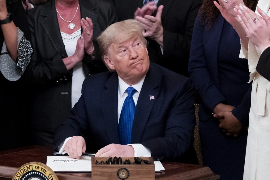 epa08182717 US President Donald J. Trump (C) signs an executive order while participating in the White House Summit on Human Trafficking, in the East Room of the White House in Washington, DC, USA, 31 ...