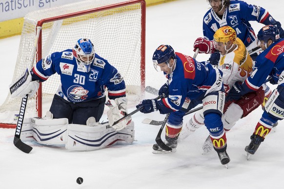 Der Zuercher Patrick Geering, Mitte, und Lukas Flueeler spielen um den Puck Harri Pesonen, Mitte, von Lausanne beim Eishockeyspiel der National League ZSC Lions gegen dem Lausanne HC im Hallenstadion  ...